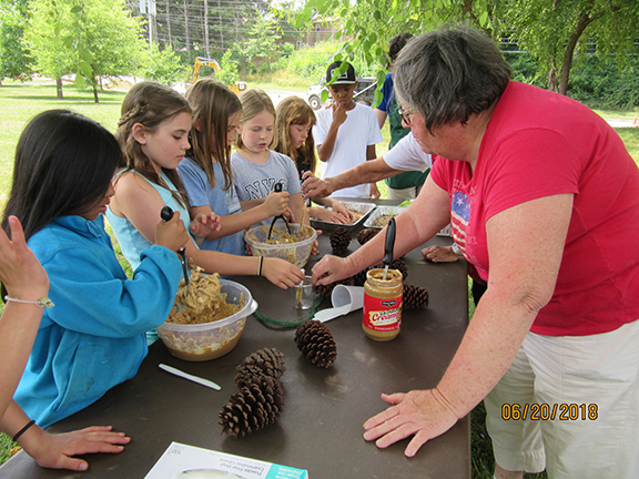 Campers mix up peanut butter for pinecone wildlife feeders.