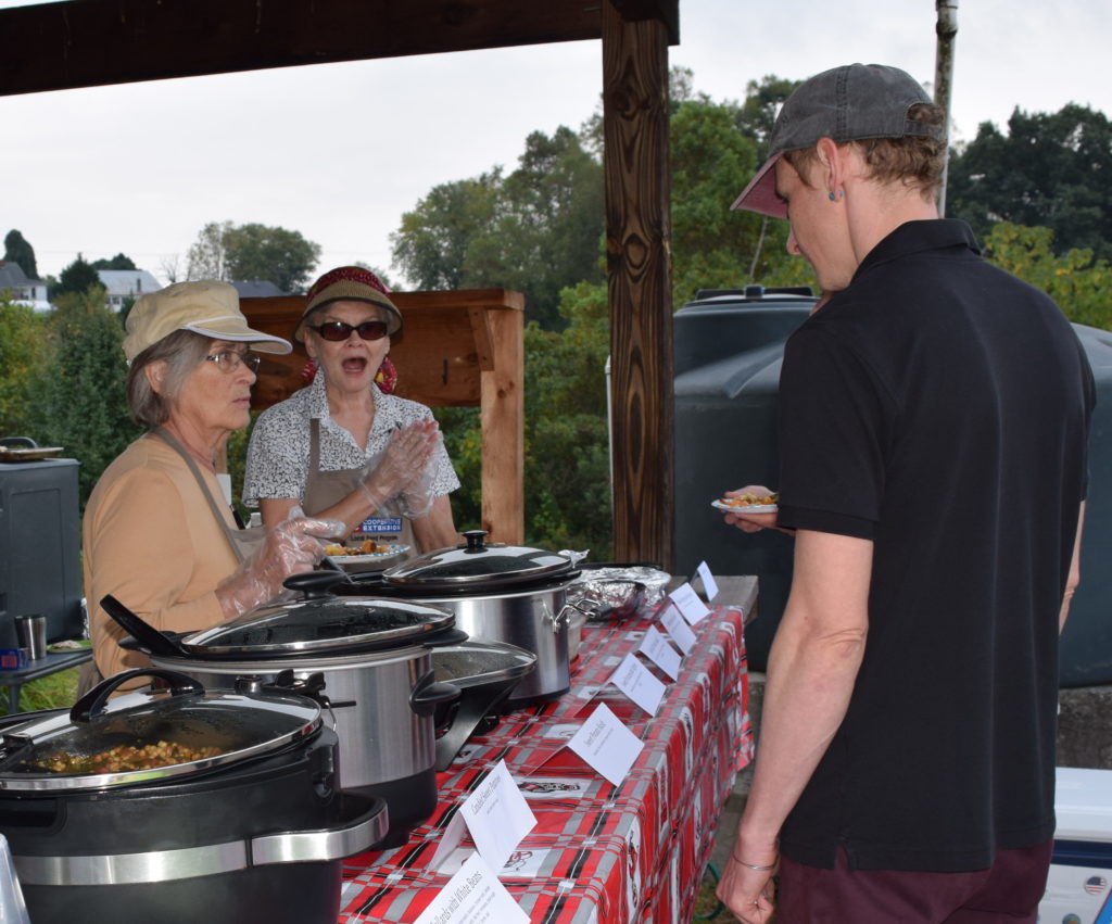 two volunteers speak with a visitor to the cooking demonstration table.