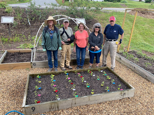 five people stand in front of a newly planted garden bed.