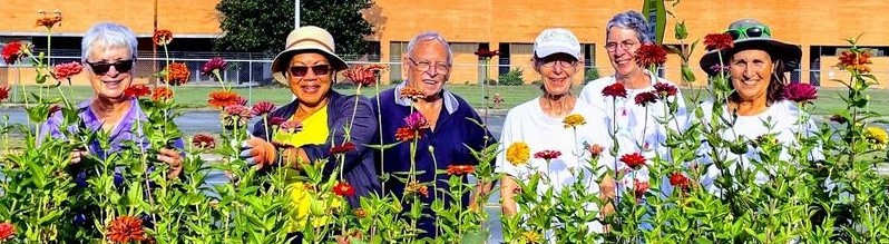 A group of volunteers stand among flowers.