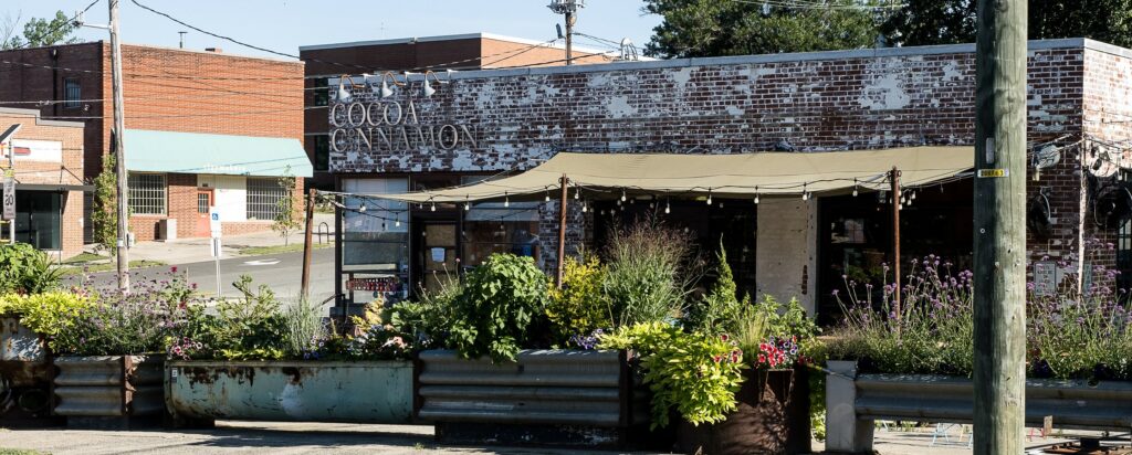 Large metal containers planted with a variety of flowers and shrubs.